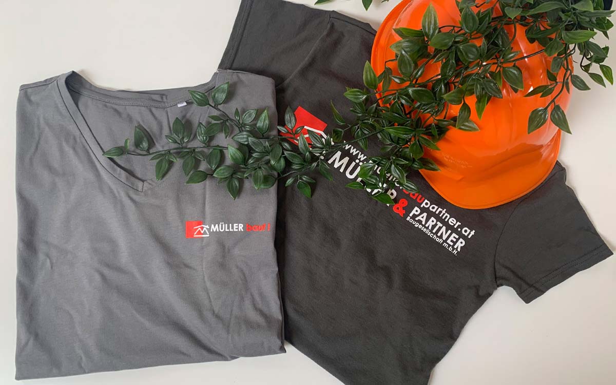 T-Shirt mit Müller Bau Logo und dekorativ orangenen Helm mit Pflanze